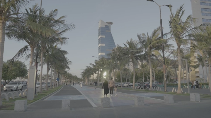 شارع محاط بالنخيل في جدة عند الغروب، لقطة واسعة.