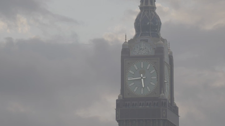 برج الساعة في مكة تحت سماء غائمة، لقطة نهارية.