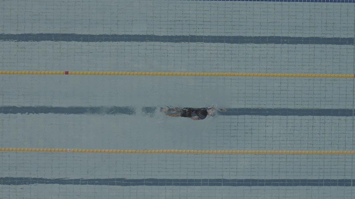شخص يسبح في مسبح، تصوير درون من الأعلى.
