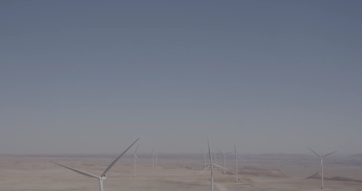 توربينات رياح في صحراء تحت سماء زرقاء، تصوير درون.