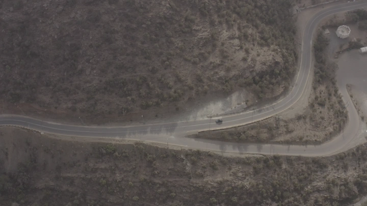 سيارة تسير على طريق جبلي متعرج، لقطة جوية .
