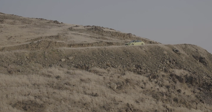 سيارة مركونة على جبل صخري في يوم غائم، لقطة بعيدة.