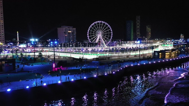 حلبة كورنيش جدة مضاءة ليلاً مع عجلة فيريس، لقطة جوية.