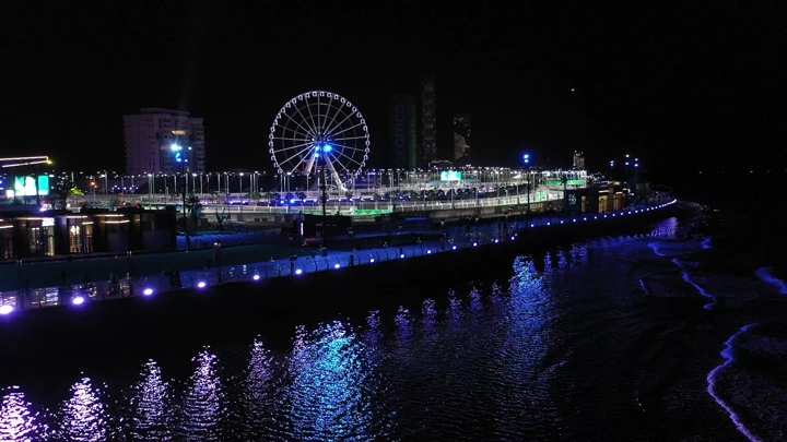 إضاءة ليلية على حلبة كورنيش جدة مع عجلة فيريس، لقطة جوية.