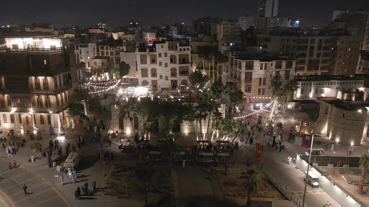 مشهد جوي لجدة القديمة ليلاً مع أضواء زينة ومباني تاريخية.