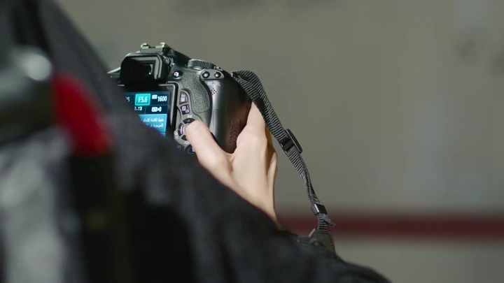 لقطة مقربة لسيدة تتحكم بكاميرا احترافية، تصوير داخلي.