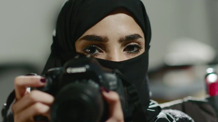 امرأة ترتدي الحجاب تصور بكاميرا احترافية، لقطة مقربة.