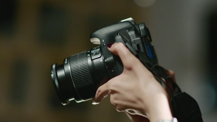 صورة مقرّبة لمصور يحمل كاميرا احترافية، تصوير داخلي.