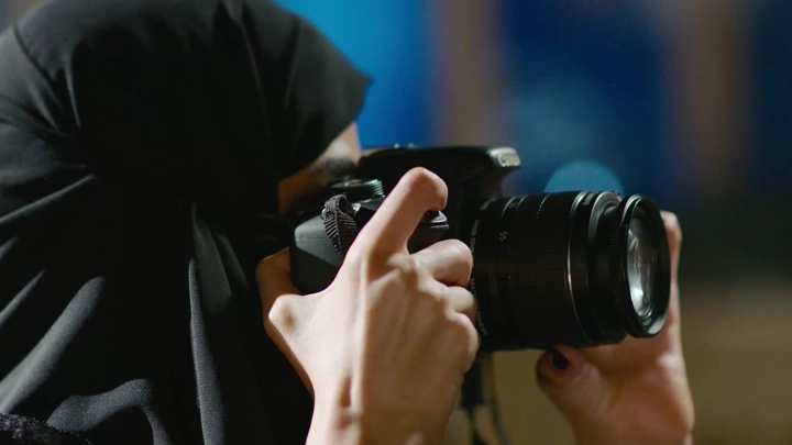 مصورة ترتدي الحجاب تلتقط صورة بكاميرا احترافية، لقطة مقربة.