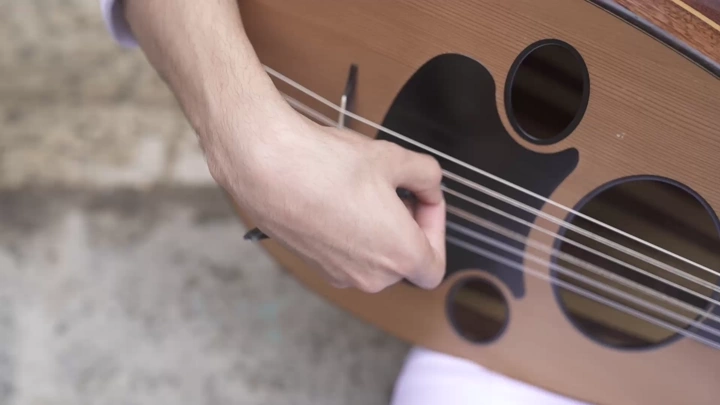 لقطة مقرّبة لشخص يعزف على العود، في ضوء النهار، لقطة قريب.