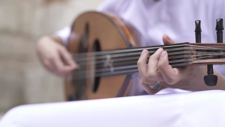 لقطة مقرّبة لشخص يعزف العود بمهارة، لقطة بورتريه.