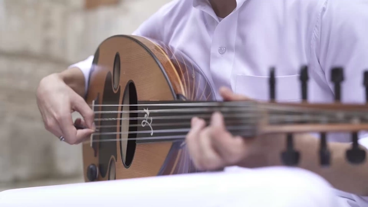 لقطة مقرّبة لشخص يعزف العود في مكان خارجي، لقطة عن قرب.