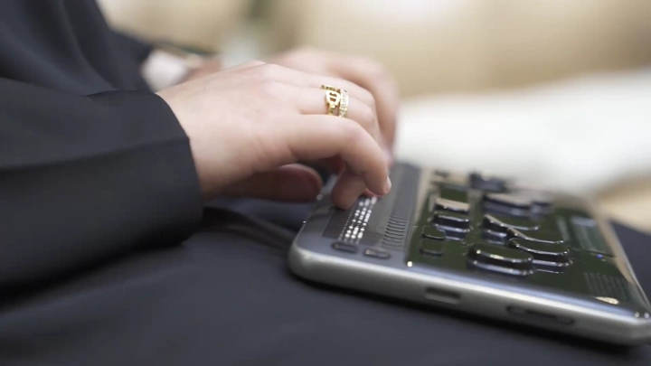 لقطة مقربة لسيدة تستخدم جهاز برايل الإلكتروني، تصوير داخلي.