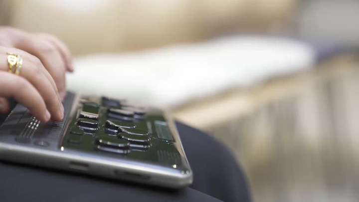 لقطة مقربة لشخص يستخدم جهاز برايل الإلكتروني، تصوير داخلي.