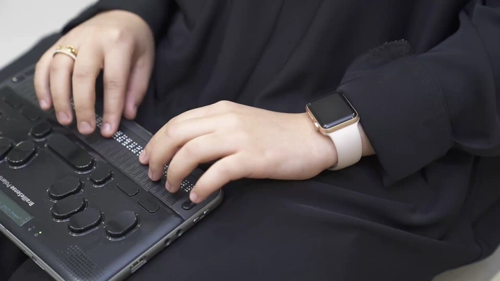 امرأة تستخدم جهاز برايل الإلكتروني للقراءة، لقطة مقربة.