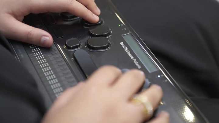 شخص يستخدم جهاز برايل الإلكتروني للقراءة، لقطة مقربة.