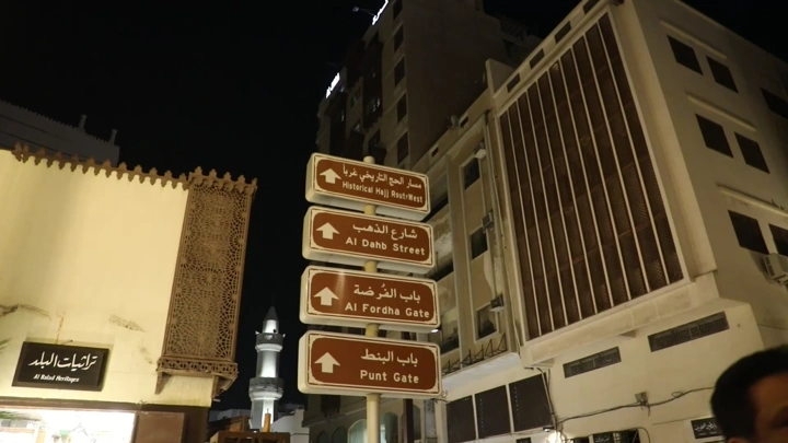 لوحة إرشادية في حي البلد التاريخي بجدة ليلاً، لقطة ليلية.