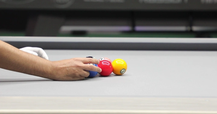 يد ترتب كرات البلياردو على الطاولة، لقطة مقرّبة.