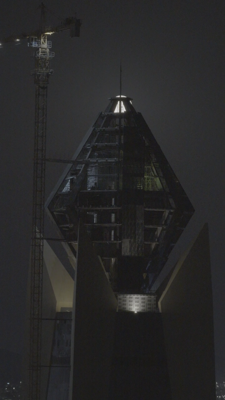 برج الجوهرة في حائل ليلاً مع رافعة بناء، لقطة ليلية.