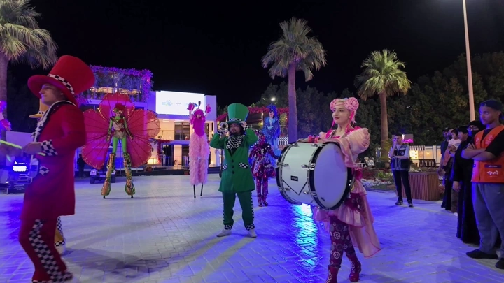 A musical band performs at the Flower Festival in Yanbu Industrial City at night, wide shot.