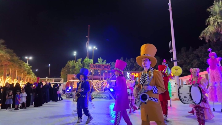 A musical band performs at the Flower Festival in Yanbu Industrial City at night, wide shot.