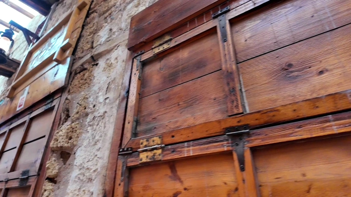 أبواب خشبية قديمة على مبنى حجري في سوق شعبي بينبع، لقطة قريبة.