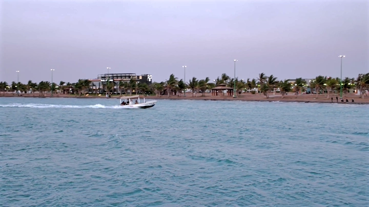 قارب سريع في البحر قرب الشاطئ عند الغروب، لقطة بانورامية.