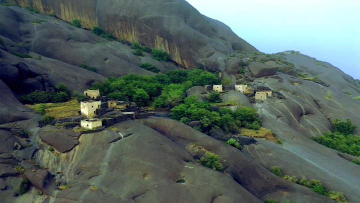 قرية غيه محاطة بالصخور والنباتات، لقطة جوية.