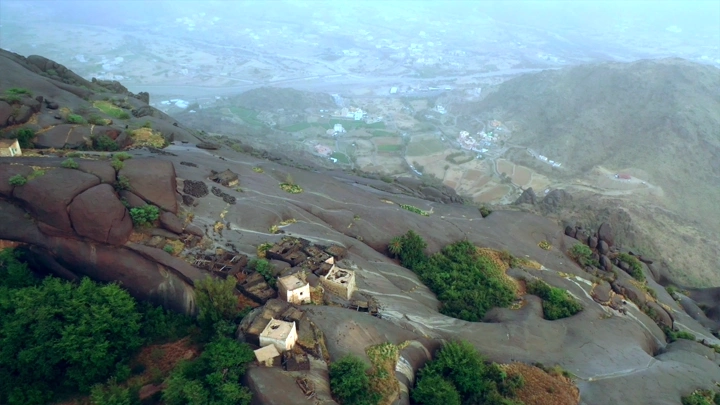 Ghey village in Asir region, aerial view showing houses and surrounding mountains.