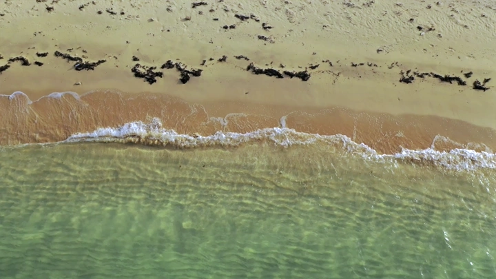 A sandy beach with waves on Farasan Island, aerial shot.
