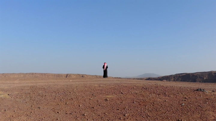 Person standing in the desert of Al-Hutaymah crater in Hail, wide shot.