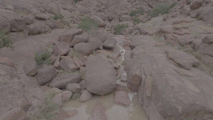 شلال صغير بين الصخور في جبال حائل، لقطة جوية.