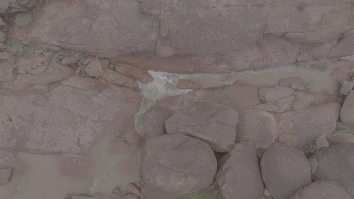 صخور جبلية مع مجرى ماء بعد الأمطار في حائل، لقطة جوية.