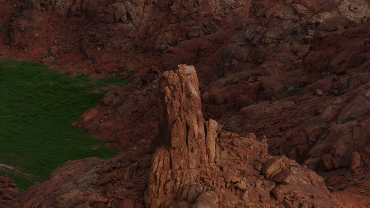 تكوين صخري مع مساحات خضراء في حائل بعد الأمطار، منظر جوي.