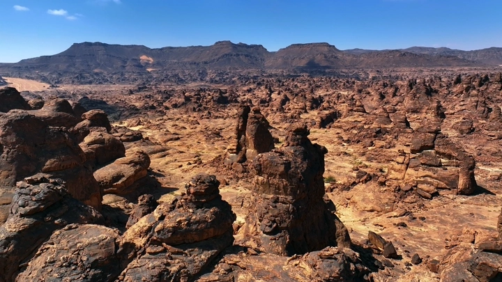 تكوينات صخرية في منطقة المسمى وسط الرمال تحت سماء زرقاء، لقطة جوية.