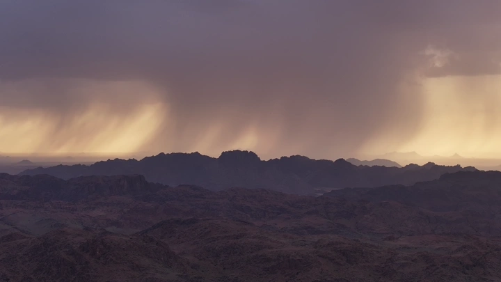 هطول الأمطار على قمم الجبال في حائل وقت غروب الشمس، منظر طبيعي.