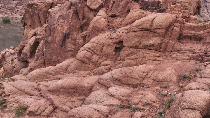 شخص يقف فوق قمة جبل عقدة امام سد ماء، لقطة جوية.