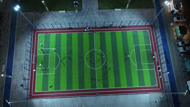 ملعب كرة قدم مضاء ليلاً، لقطة من الأعلى.