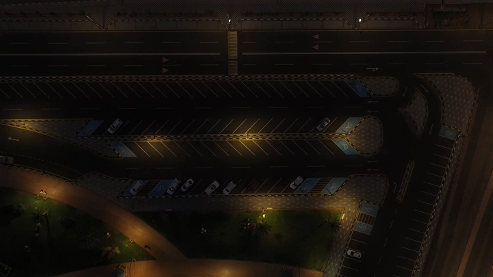 موقف سيارات مضاء ليلاً في حديقة حائل العامة، لقطة جوية إسقاطية.