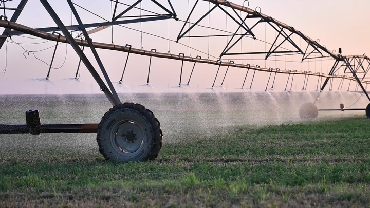 نظام رش محوري في حقل زراعي عند الغروب، لقطة جانبية.