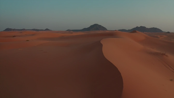 رمال النفود الكبير مع جبال في الأفق، لقطة جوية.