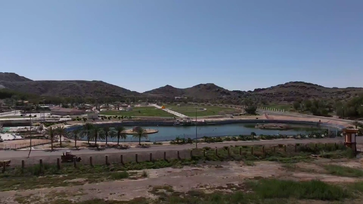 Al Samra Park in Hail with a lake and mountains in the background, aerial shot.