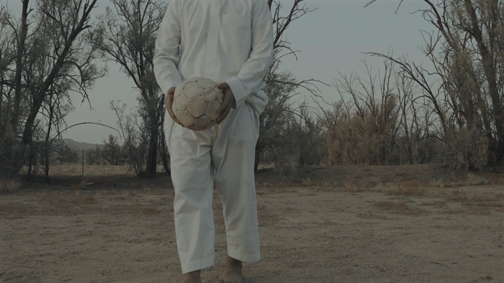 شخص يحمل كرة قدم في صحراء مشهد من التراث، لقطة أرضية.