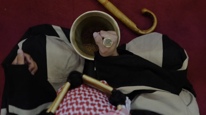 شخص يدق النجر لتحضير القهوة السعودية، لقطة من الأعلى.