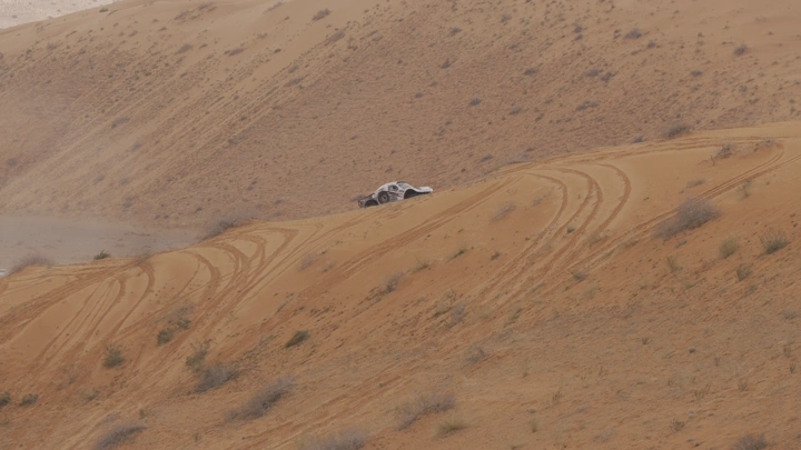 سيارة رالي على كثبان رملية في حائل، لقطة بعيدة.
