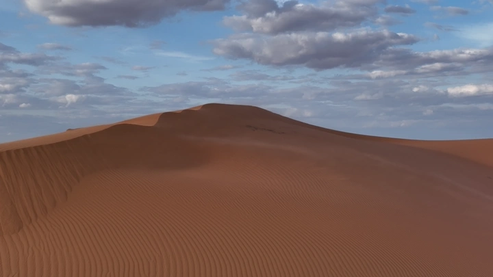 كثبان رملية في شمال السعودية تحت سماء غائمة، لقطة واسعة.