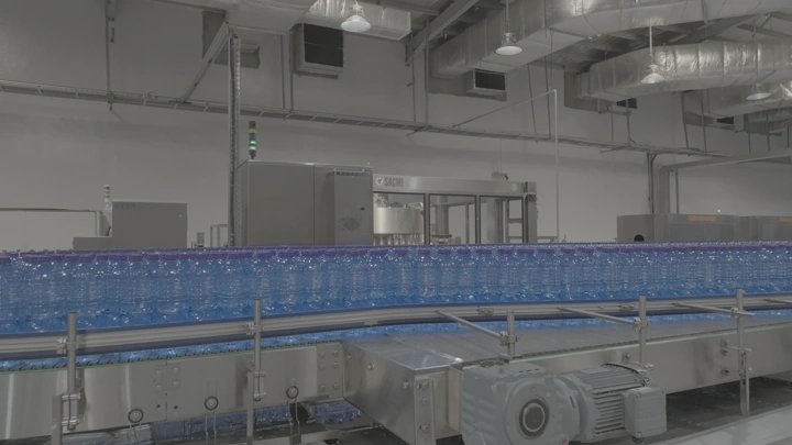 خط إنتاج زجاجات مياه بلاستيكية في مصنع، لقطة داخلية.