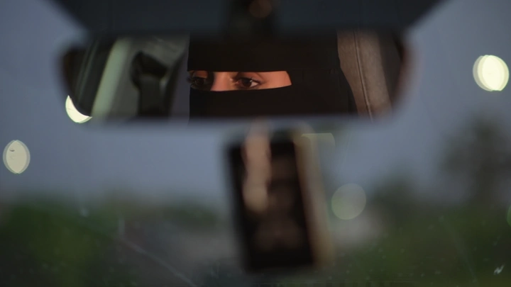 انعكاس امرأة منقبة في مرآة السيارة، لقطة مسائية.