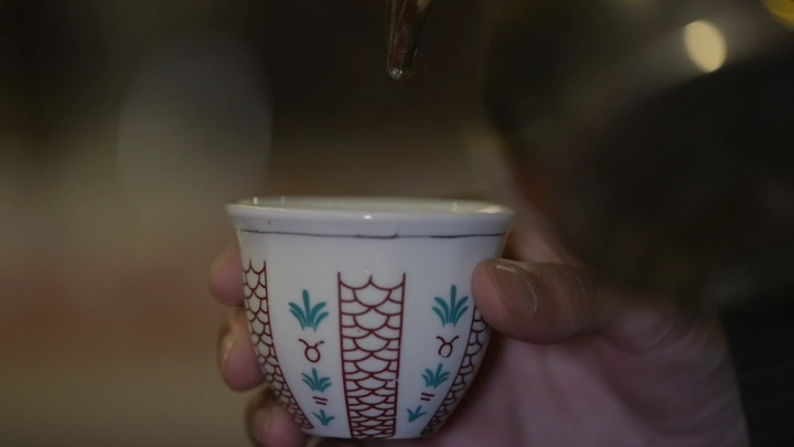 صب القهوة السعودية في فنجان تقليدي، لقطة مقربة.