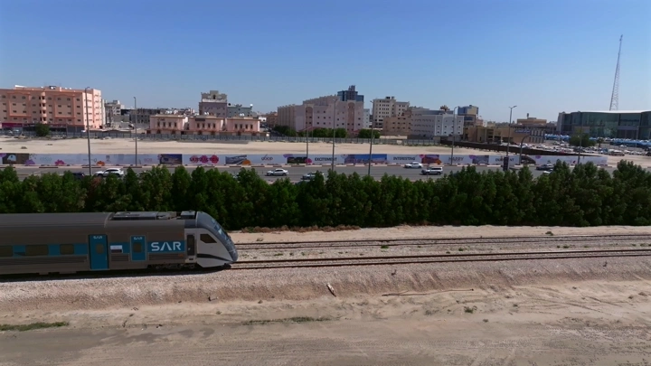 قطار يسير بجانب مدينة في وضح النهار، لقطة جوية.